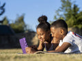 Siblings using tablet in back yard