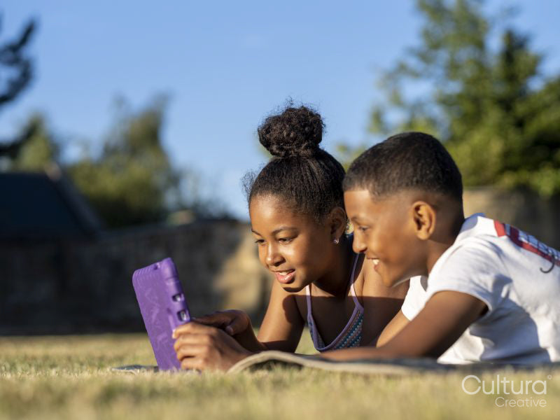 Siblings using tablet in back yard