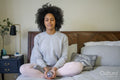 Young woman meditating on bed