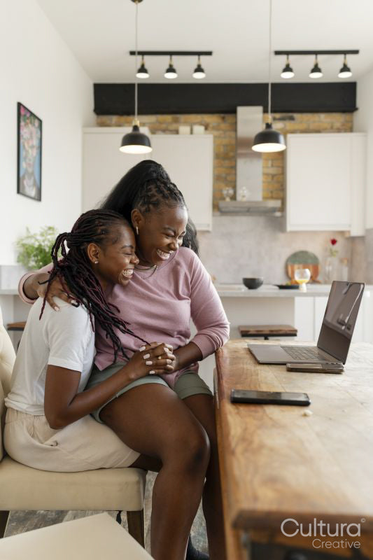 Happy couple using laptop while sitting on chair at home