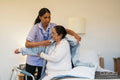Nurse helping senior lady in her room at nursing home