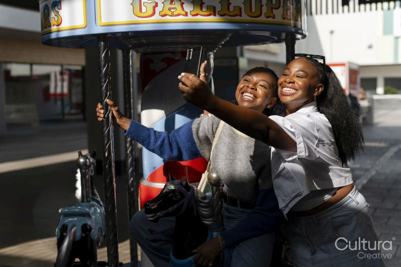 Young female friends taking selfie on merry-go-round