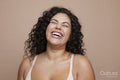 Studio shot of laughing young woman with curly hair