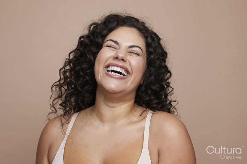 Studio shot of laughing young woman with curly hair