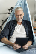 Smiling mature man using digital tablet in hammock