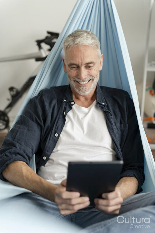 Smiling mature man using digital tablet in hammock