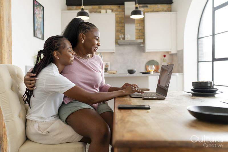 Happy couple using laptop while sitting on chair at home