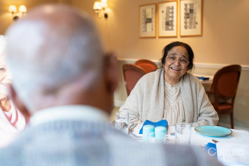 Senior people talking at table during meal in nursing home