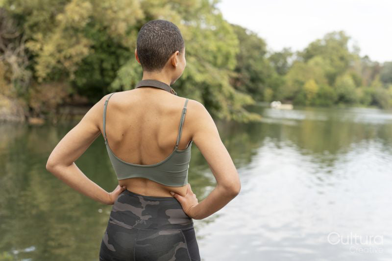 Rear view of athletic woman standing by pond in park