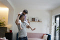 Father carrying daughter on shoulders at home