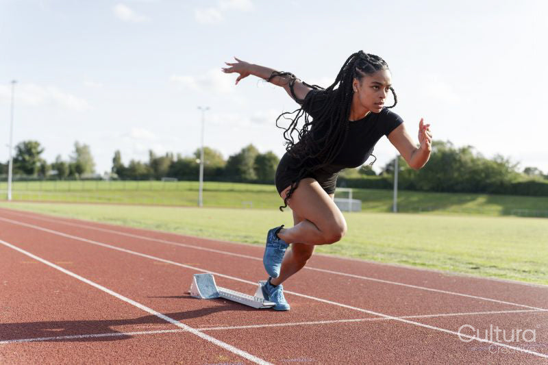 Female athlete sprinting off starting line at stadium