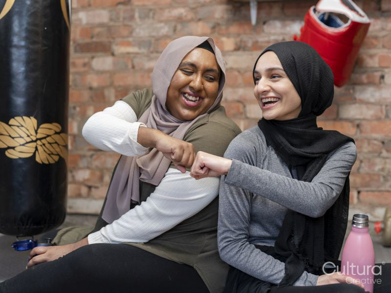 Smiling women doing fist bump in gym