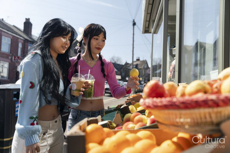 Young women buying fruit in street