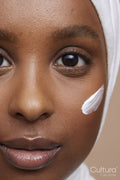Studio portrait of young woman in white hijab applying face cream