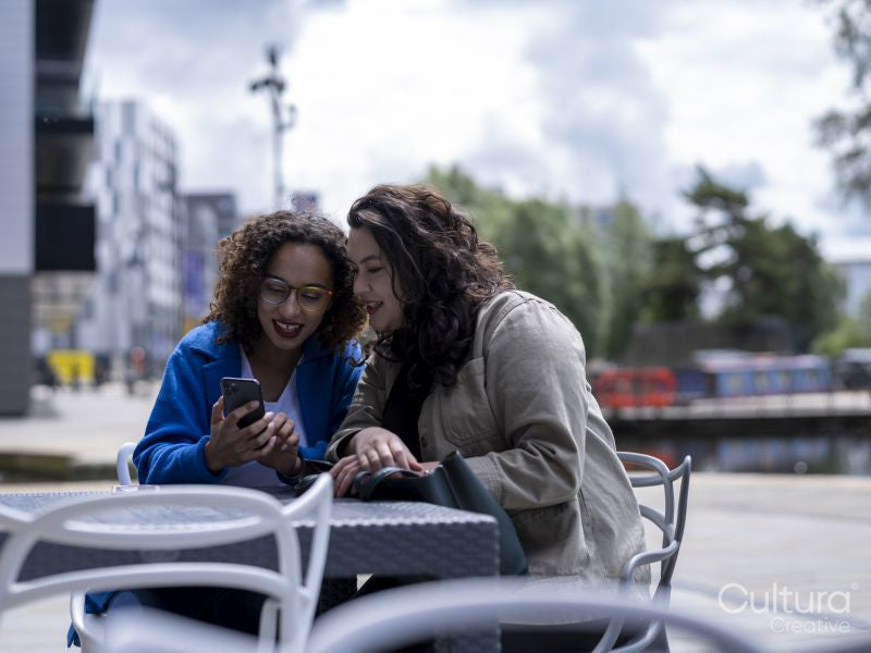 Smiling couple looking at smart phones at sidewalk cafe table