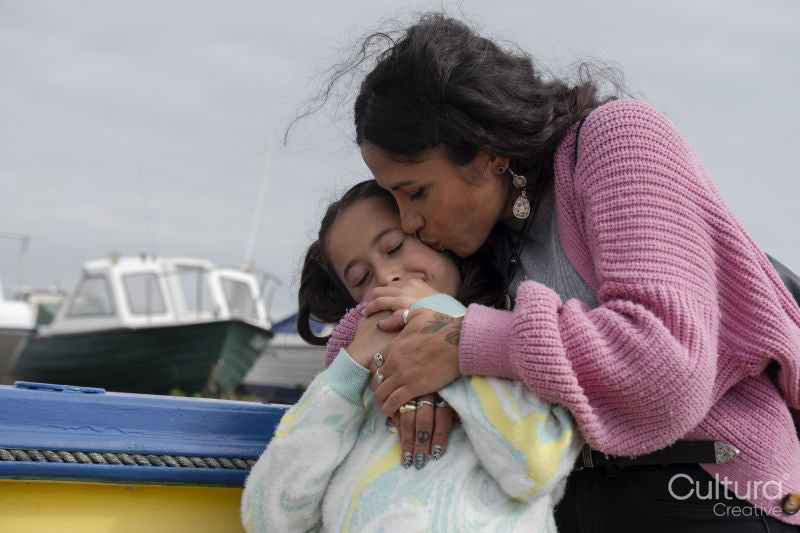 Portrait of mother kissing daughter in harbor