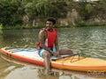 Young man sitting on paddleboard on lake