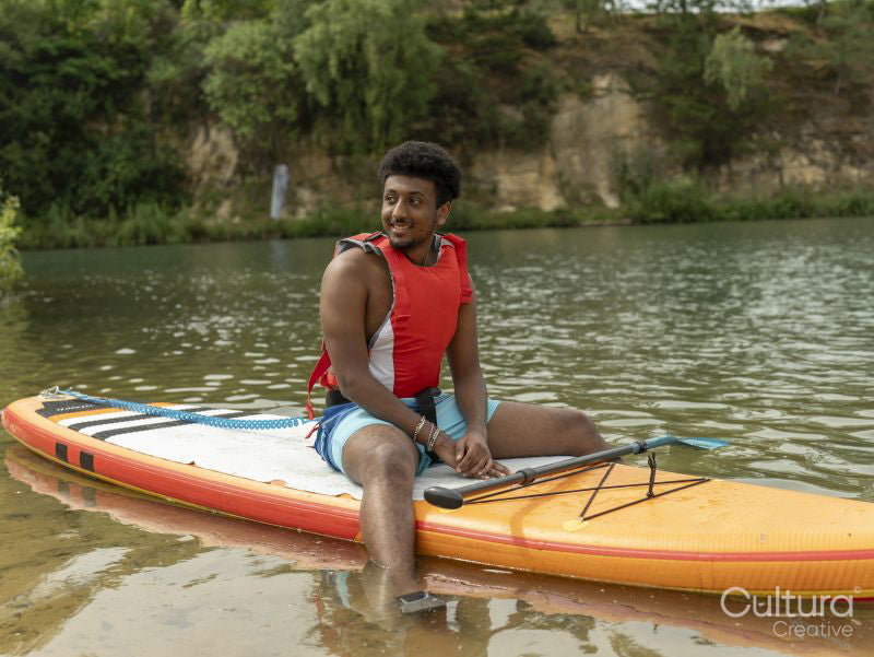 Young man sitting on paddleboard on lake
