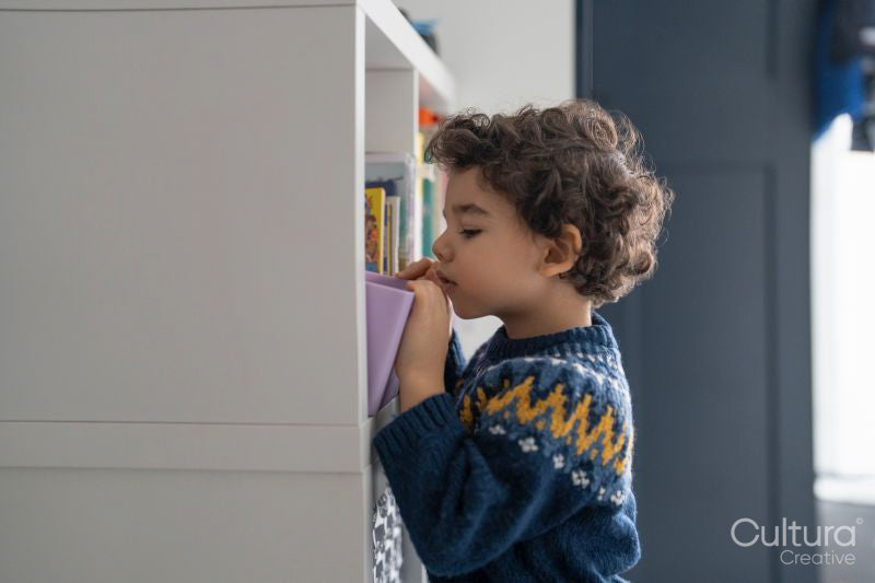 Boy searching bookshelf at home