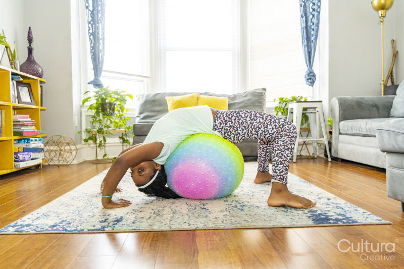 Girl exercising with fitness ball in her room