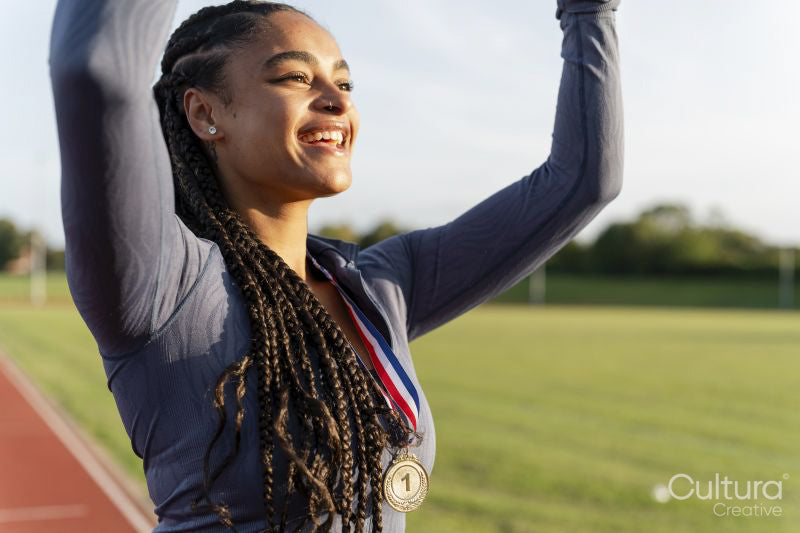 Portrait of female athlete celebrating with medal