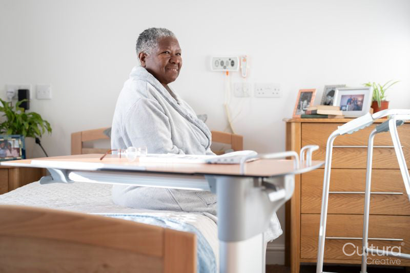 Smiling senior woman in bathrobe sitting on bed in nursing home