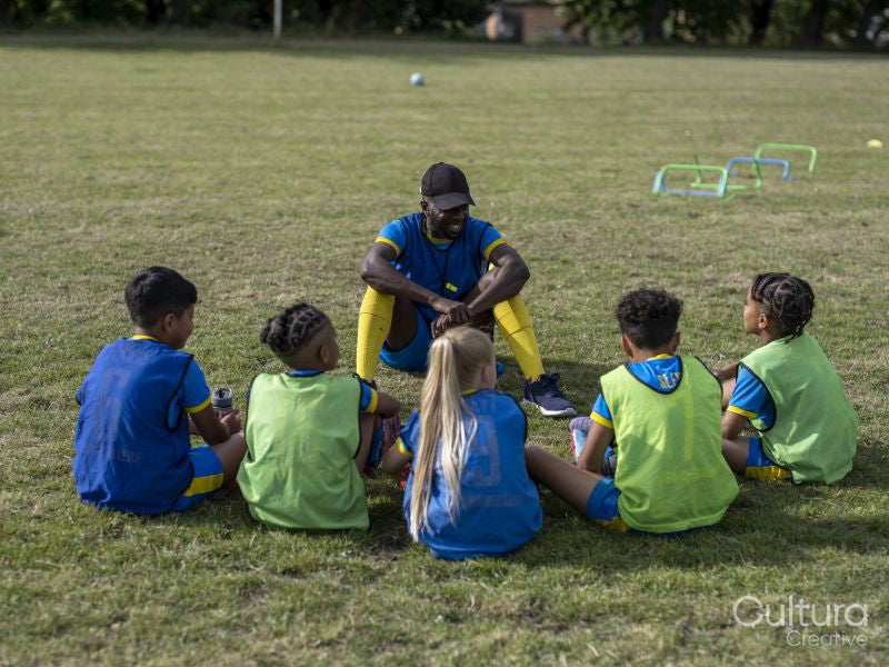 Coach giving instructions to kids on soccer field