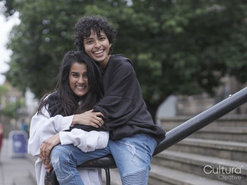 Female couple hugging on stairs in city