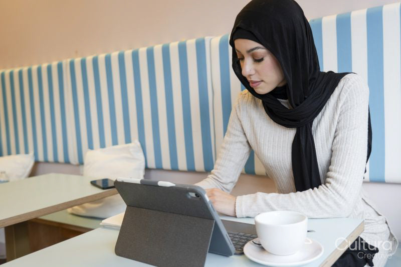 Young woman in hijab using tablet in cafe