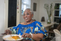 Smiling senior woman eating dinner at home
