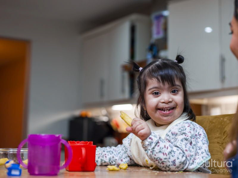 Portrait of girl with Down syndrome eating at table
