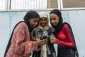 Smiling young women wearing hijabs looking at smart phone