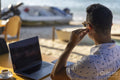 Man using laptop at beach cafe