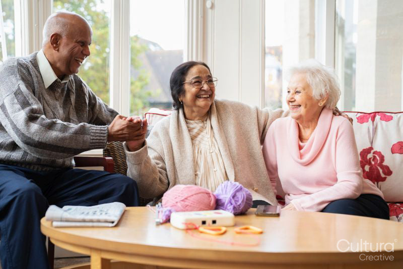 Smiling senior couple and senior woman sitting together in living room at nursing home
