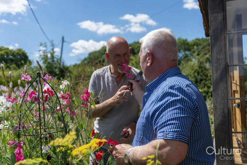 Senior male couple smelling flowers