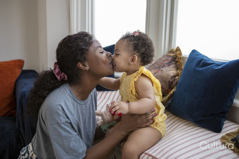 Mother kissing baby daughter at home