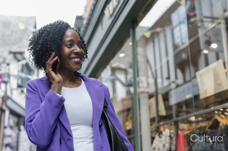 Smiling woman talking by smart phone in city