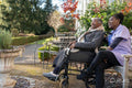Smiling nurse and senior woman in wheelchair relaxing in park