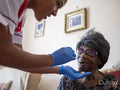 Nurse taking care of elderly woman, taking nasal sample for testing