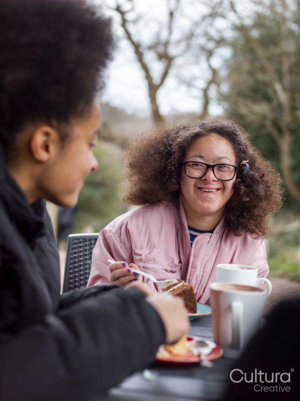 Two girls eating cakes in cafe