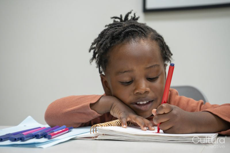 Girl sitting at table and drawing in notepad