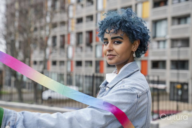 Portrait of smiling young woman holding colorful ribbon