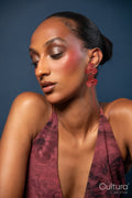 Woman in a burgundy dress with red earrings on a blue background