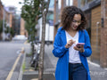 Smiling woman using smart phone on street