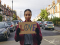 Woman on street holding protest sign with symbol of peace