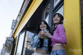 Young women standing in front of building with sweet drinks