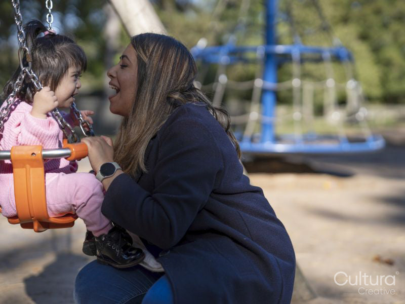 Mother swinging daughter with Down syndrome on playground swing ...