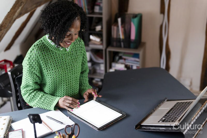 Smiling businesswoman working on digital tablet by desk in office