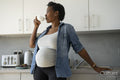 Pregnant woman drinking tea in kitchen