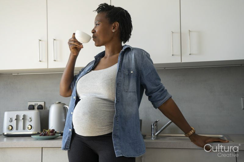 Pregnant woman drinking tea in kitchen